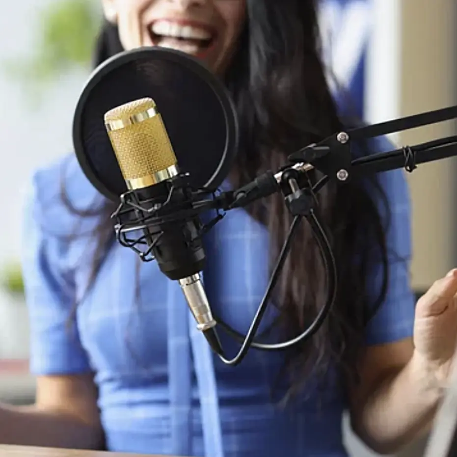 Image of a woman speaking into a microphone to record her voice.